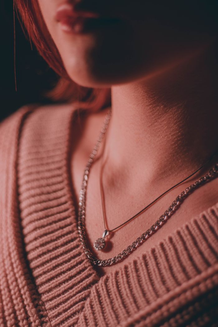Close-up of an elegant necklace worn over a cozy sweater, exuding luxury.