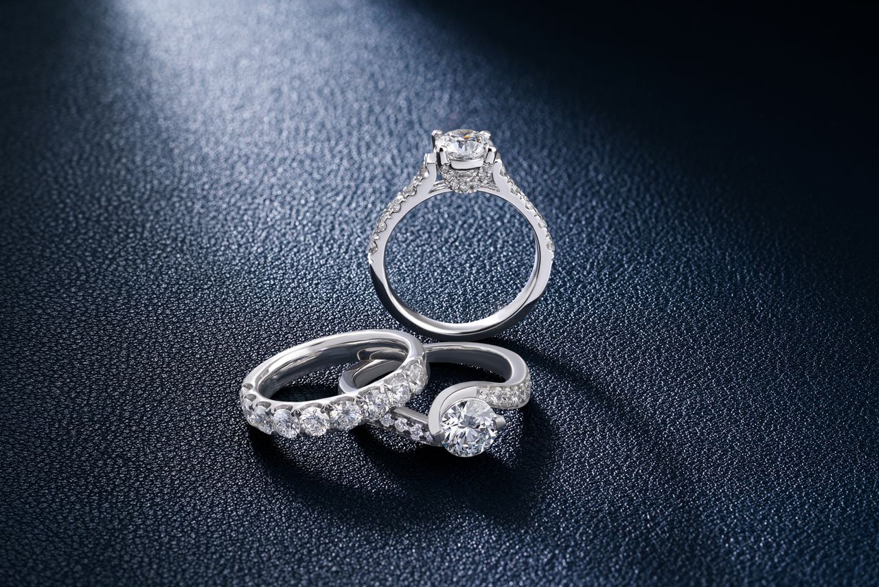 Close-up of luxurious diamond engagement and wedding rings on a textured surface, showcasing elegance and craftsmanship.