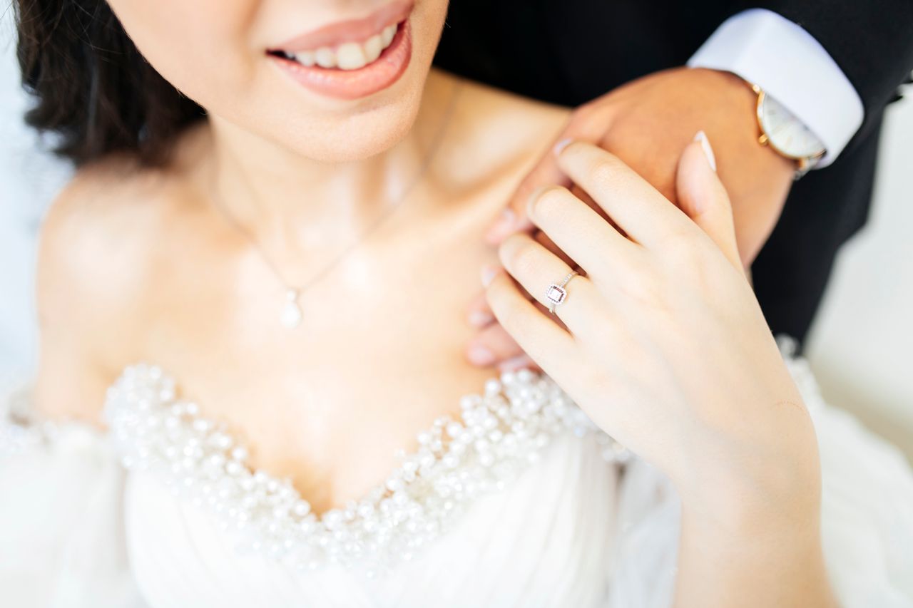 Close-up of a bride's hand with a ring, embraced by the groom on a wedding day.