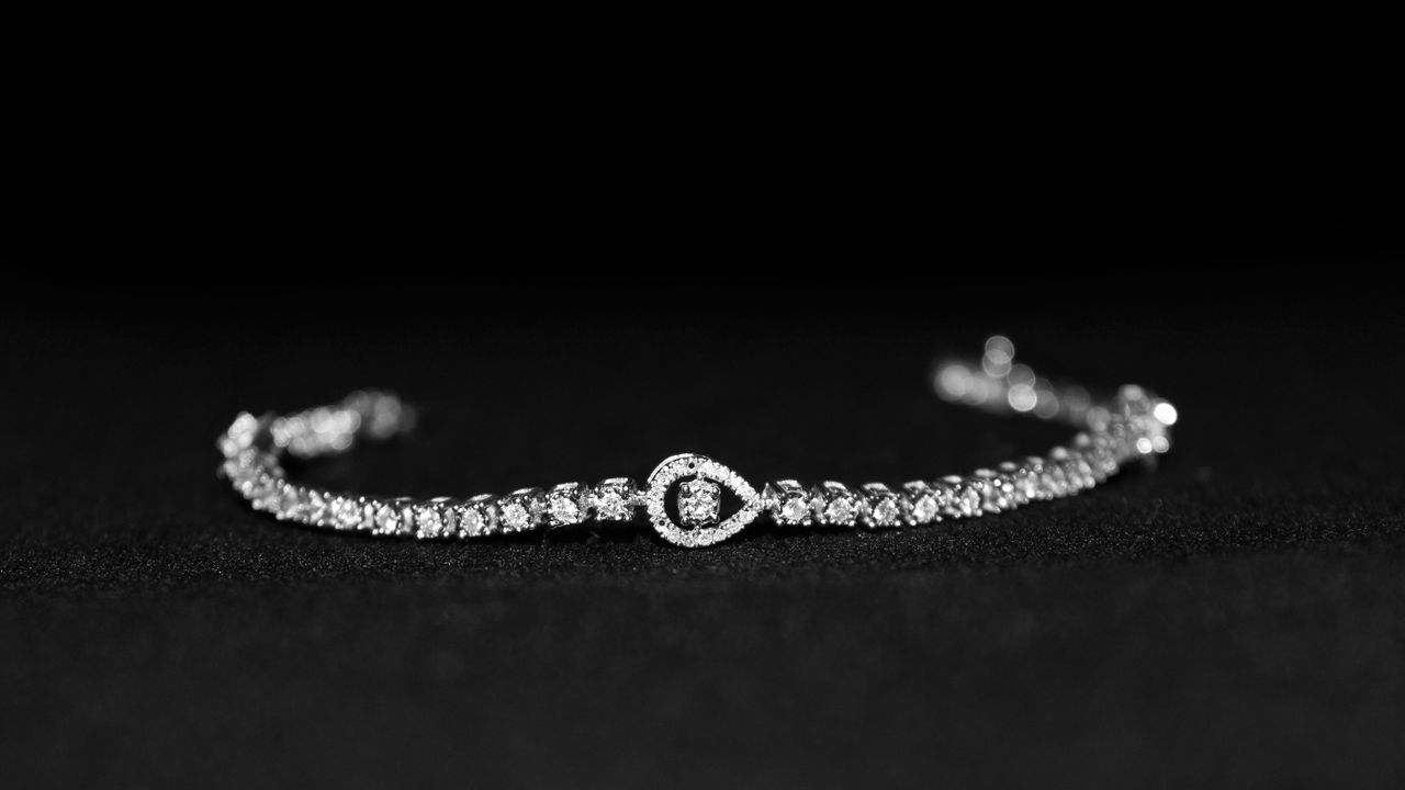 Close-up of a luxurious diamond bracelet with a black backdrop, showcasing elegance.