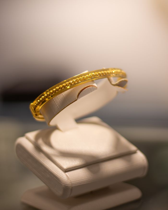 Close-up of a luxurious gold bracelet elegantly displayed on a stand.