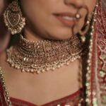 Close-up of a bride wearing ornate traditional jewelry and intricate red attire.
