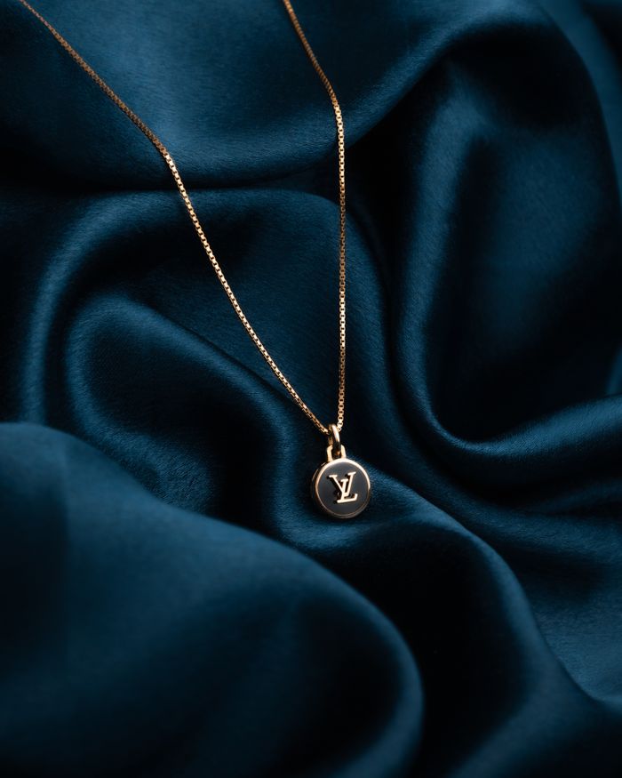Gold pendant necklace displayed on deep blue silk, capturing elegance and luxury.